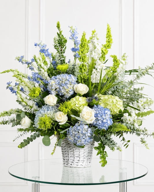 Cesta funeraria azul y blanca premium con hortensias y rosas para condolencias en Madrid