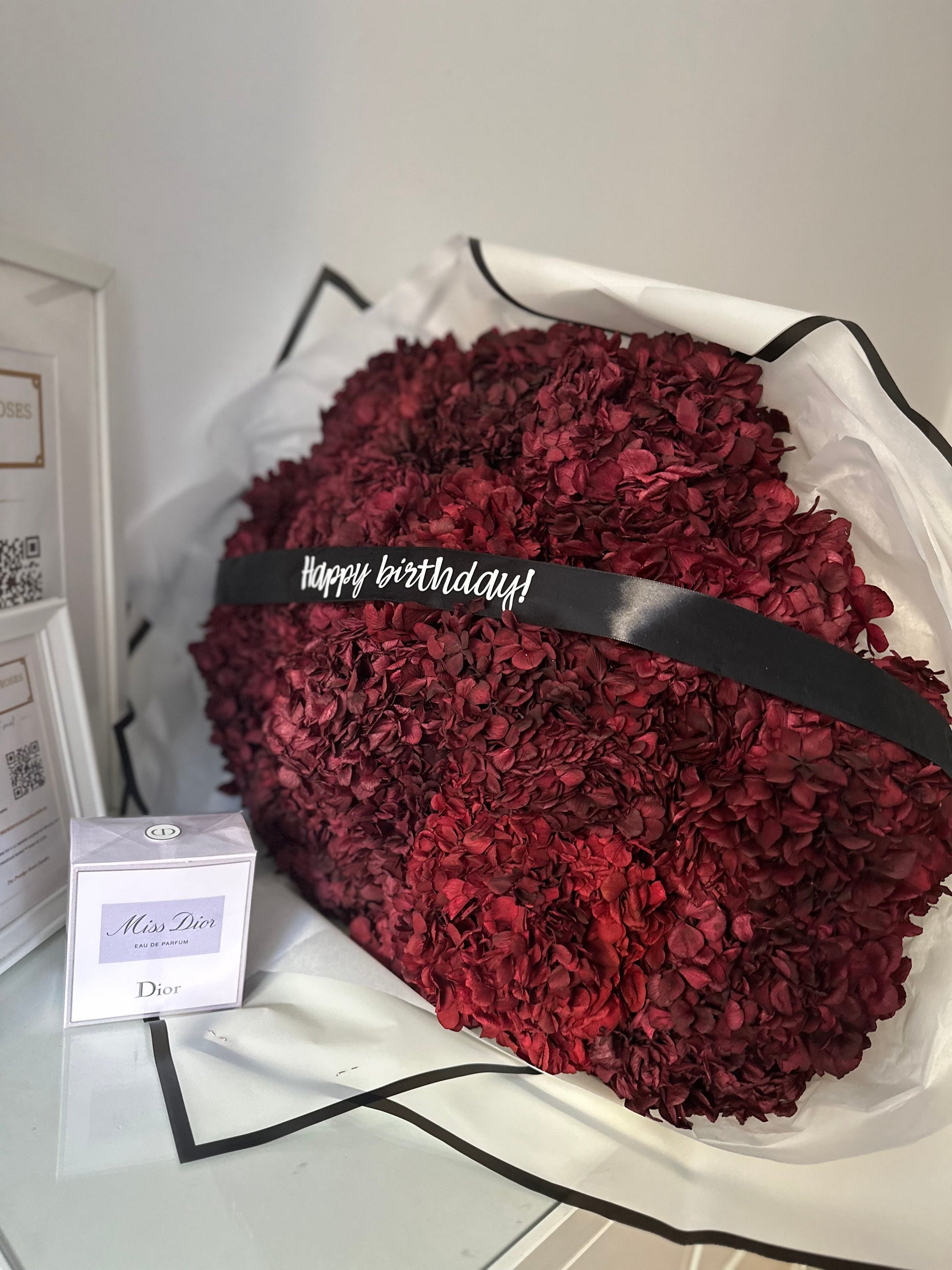 Corazón de hortensias eternas en tono burdeos para funerales, arreglo floral premium en forma de corazón con cinta  diseño exclusivo de The Prestige Funerarias Madrid.